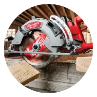 Red and silver circular saw cutting through stacked wooden planks inside a workshop with wooden beams in the background.